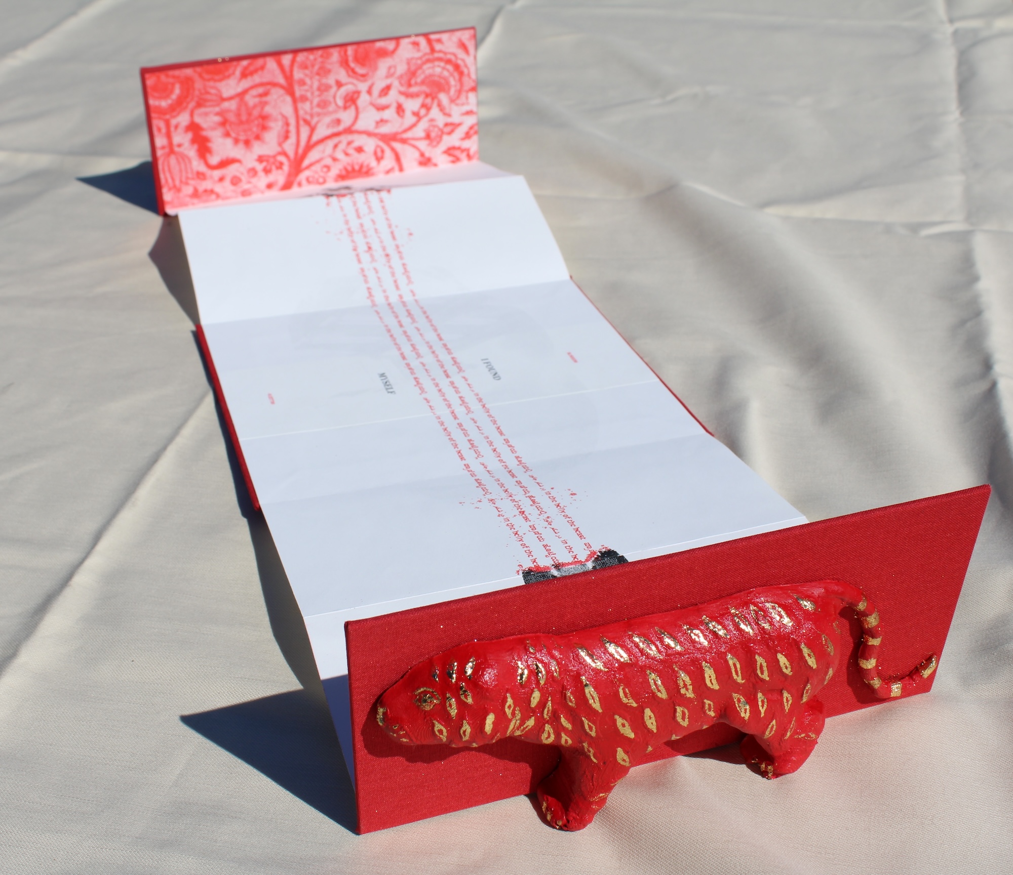 an bright red accordion book with a tiger molded on the cover. Inside the tiger's belly is Robert Clive